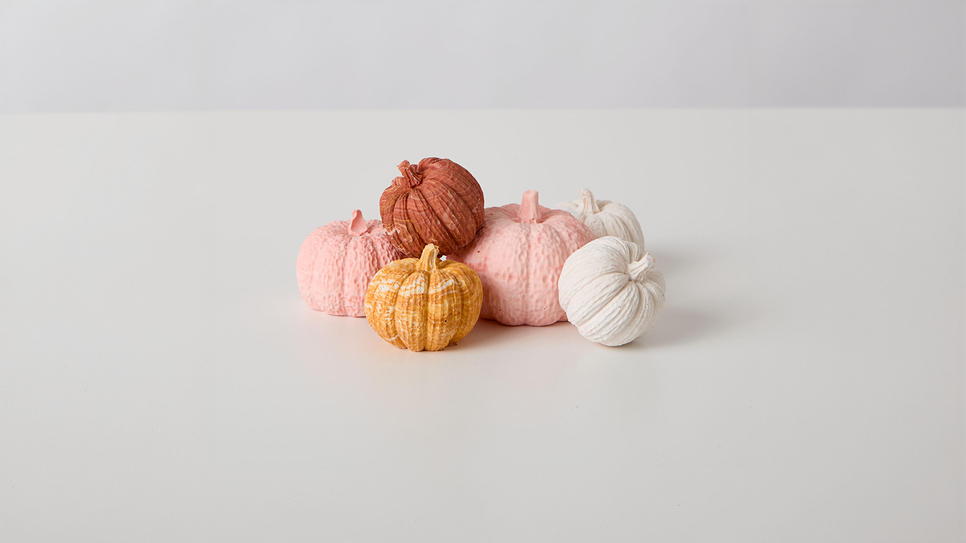 A collection of pumpkin ornaments made of Jesmonite a sustainable and eco-friendly material