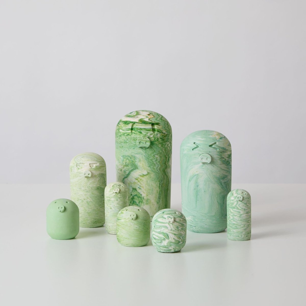 A collection of green pig ornaments made from jesmonite a sustainable and eco friendly material for interiors