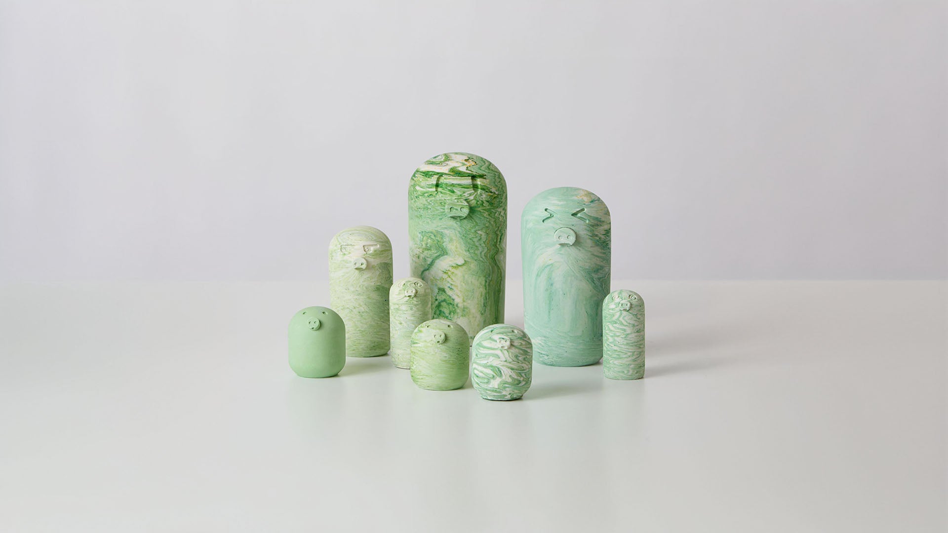 A collection of green pig ornaments in various shapes and sizes, made from eco-friendly jesmonite