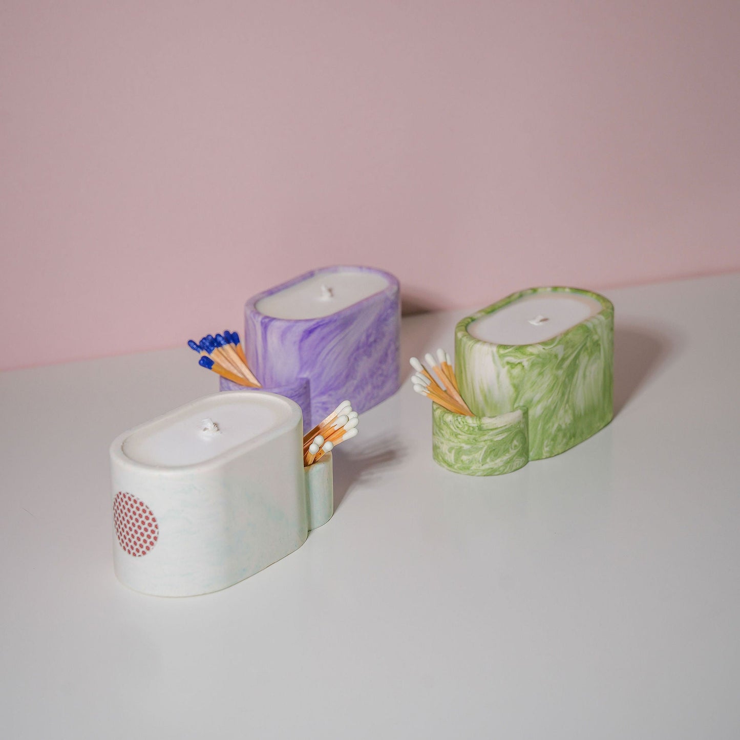 A selection of jesmonite candle holders with matches in various colours. 