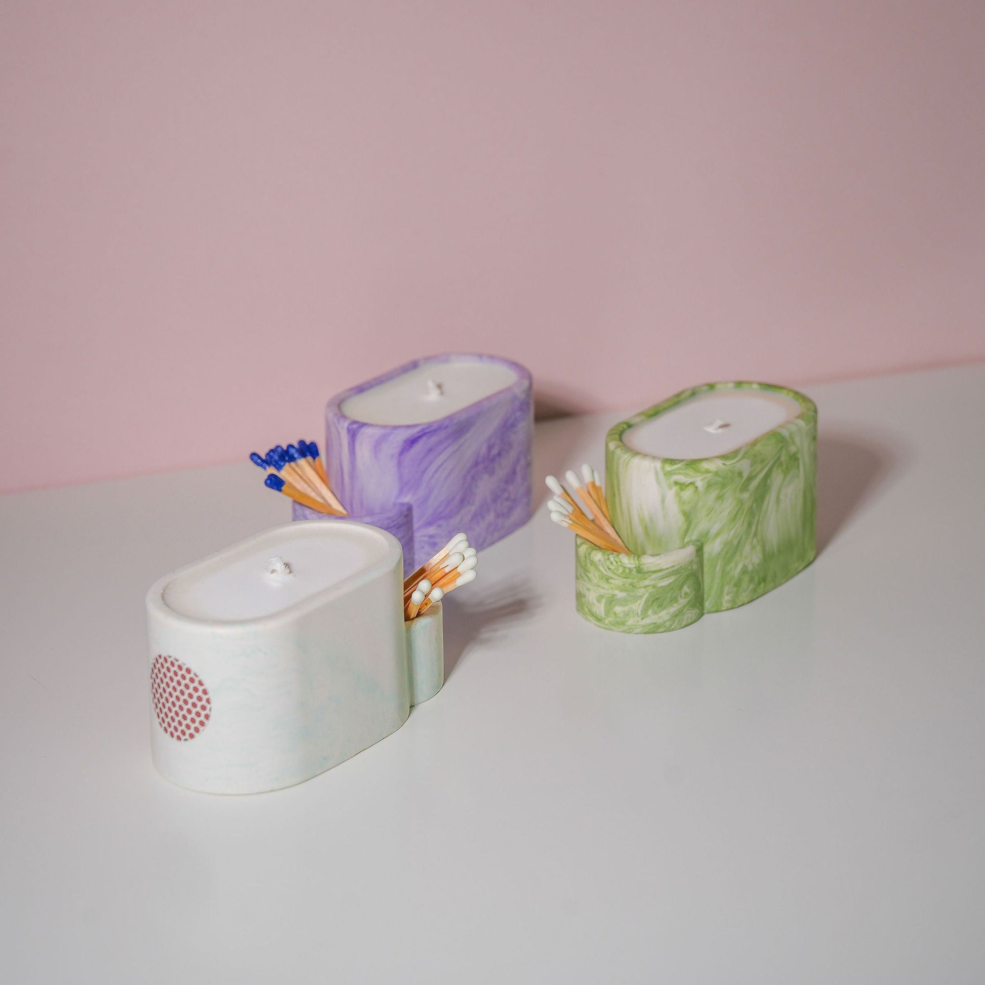 A selection of jesmonite candle holders with matches in various colours. 