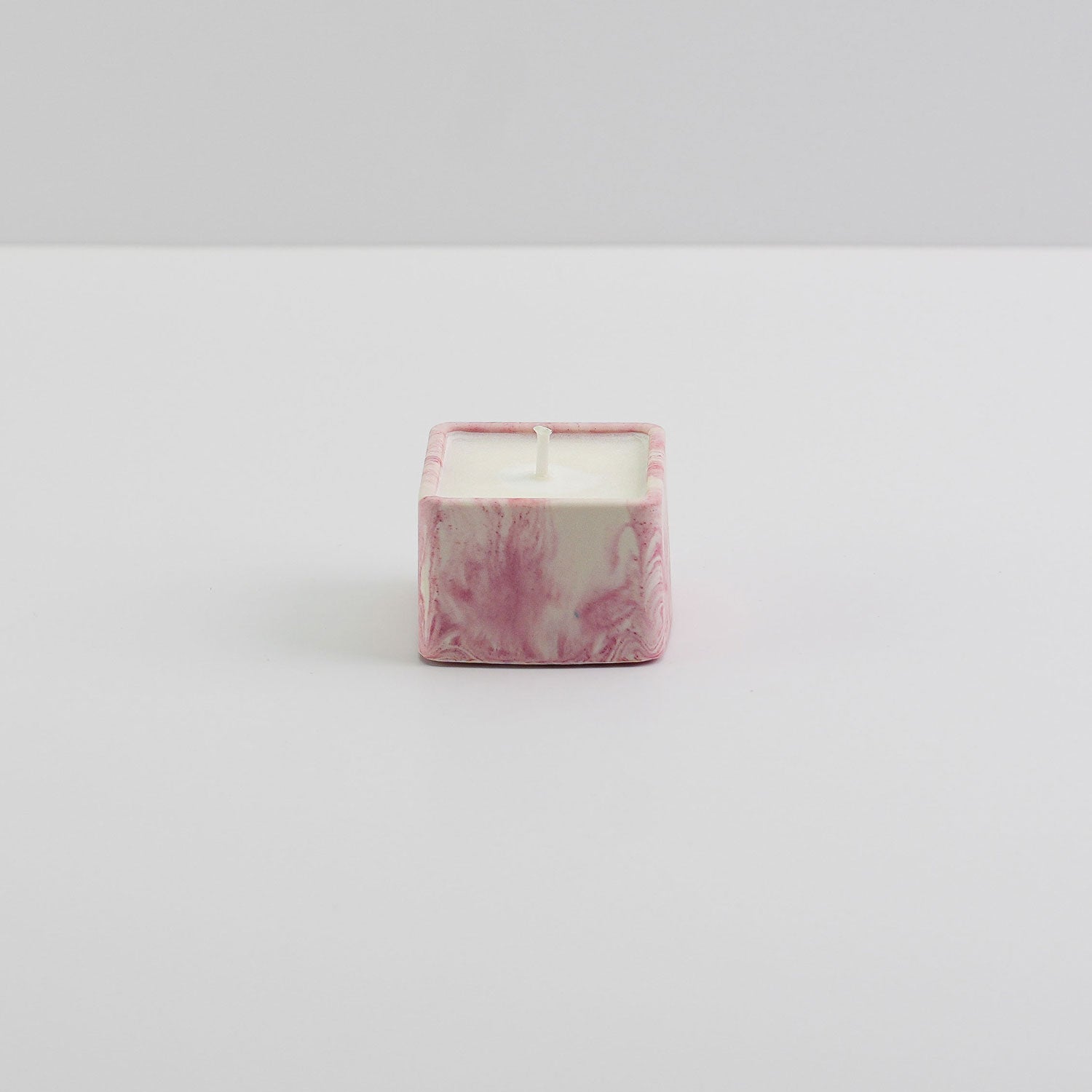 A small, square jesmonite candle holder in pink