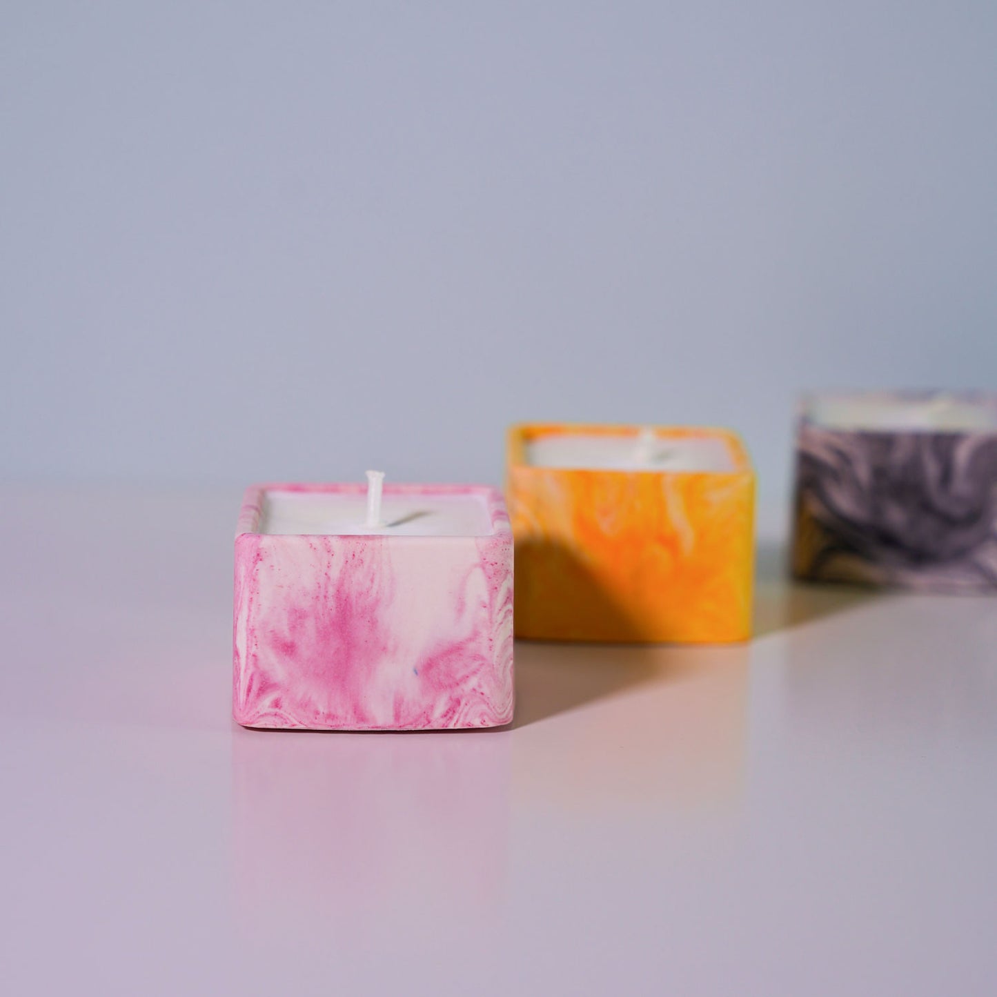 A selection of small, square candle holders in a range of colours